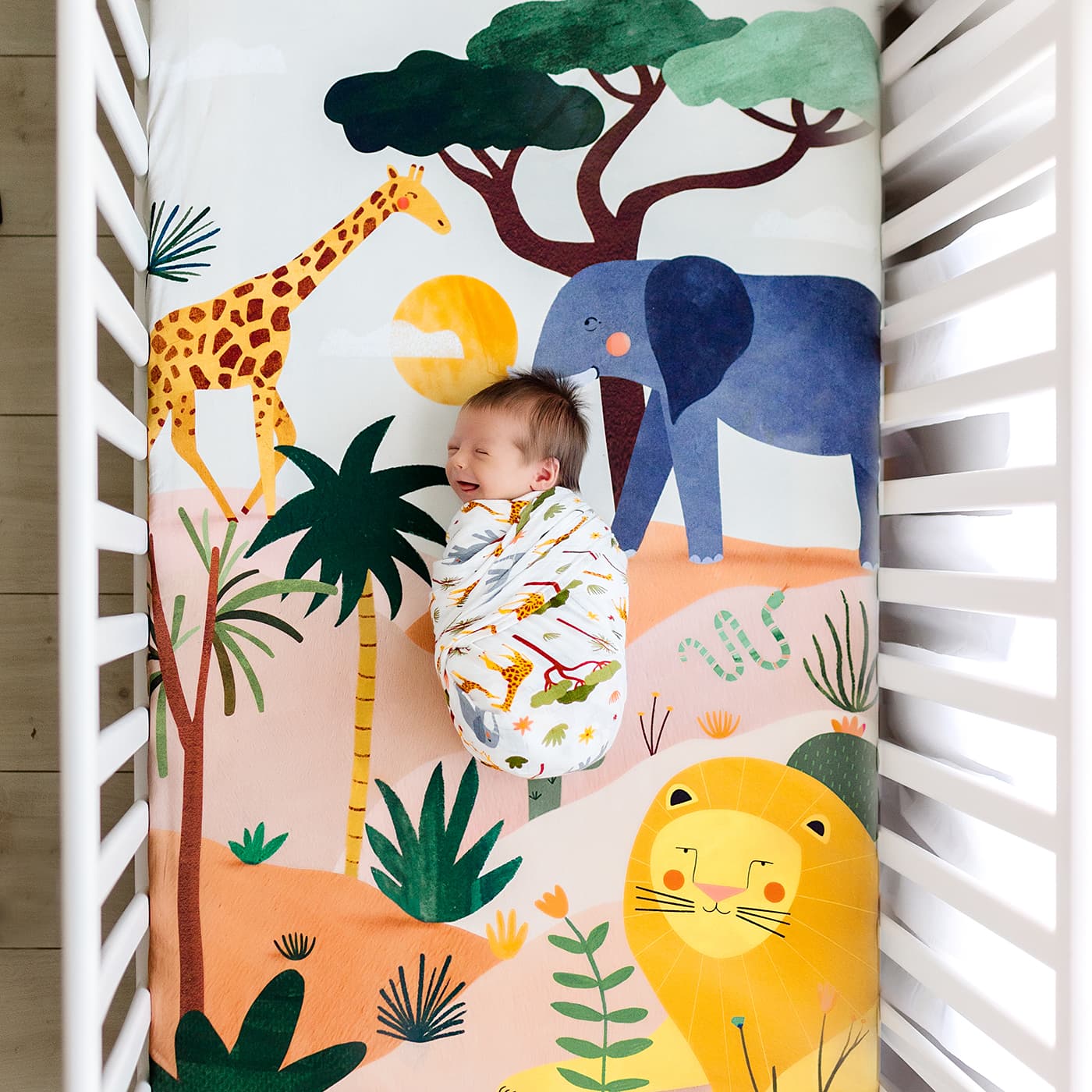 safari crib sheet and matching swaddle, crib sheet and swaddle feature elephants, lions and giraffes