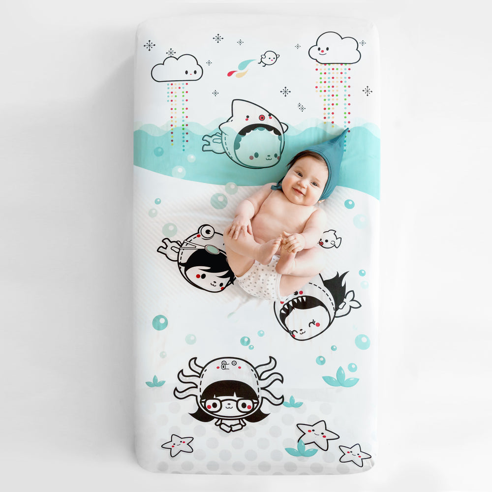 Fitted baby crib sheet by Rookie Humans, Dive In. Illustrated by Elisa Sassi. Designed for the modern nursery, packaged to make a unique baby shower gift. Underwater theme, under the sea nursery theme, under the ocean nursery theme, nautical nursery theme.