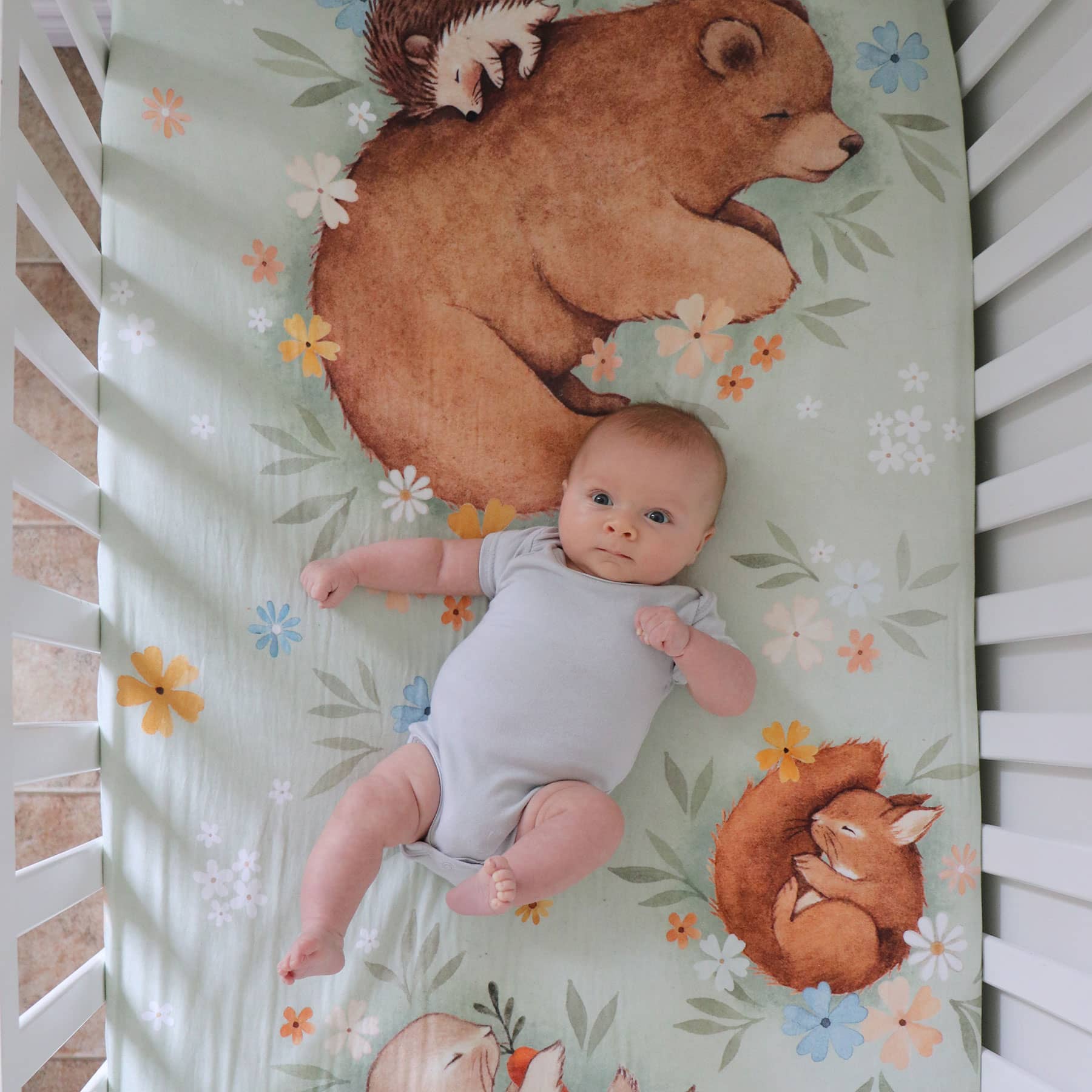 Rookie Humans crib sheet Enchanted Meadow. Floral crib sheet with sleeping bear, squirrel, hedgehog and bunny. Light green crib sheet, woodland theme, floral theme. Boho nursery, floral nursery, boho crib sheet, boho baby.