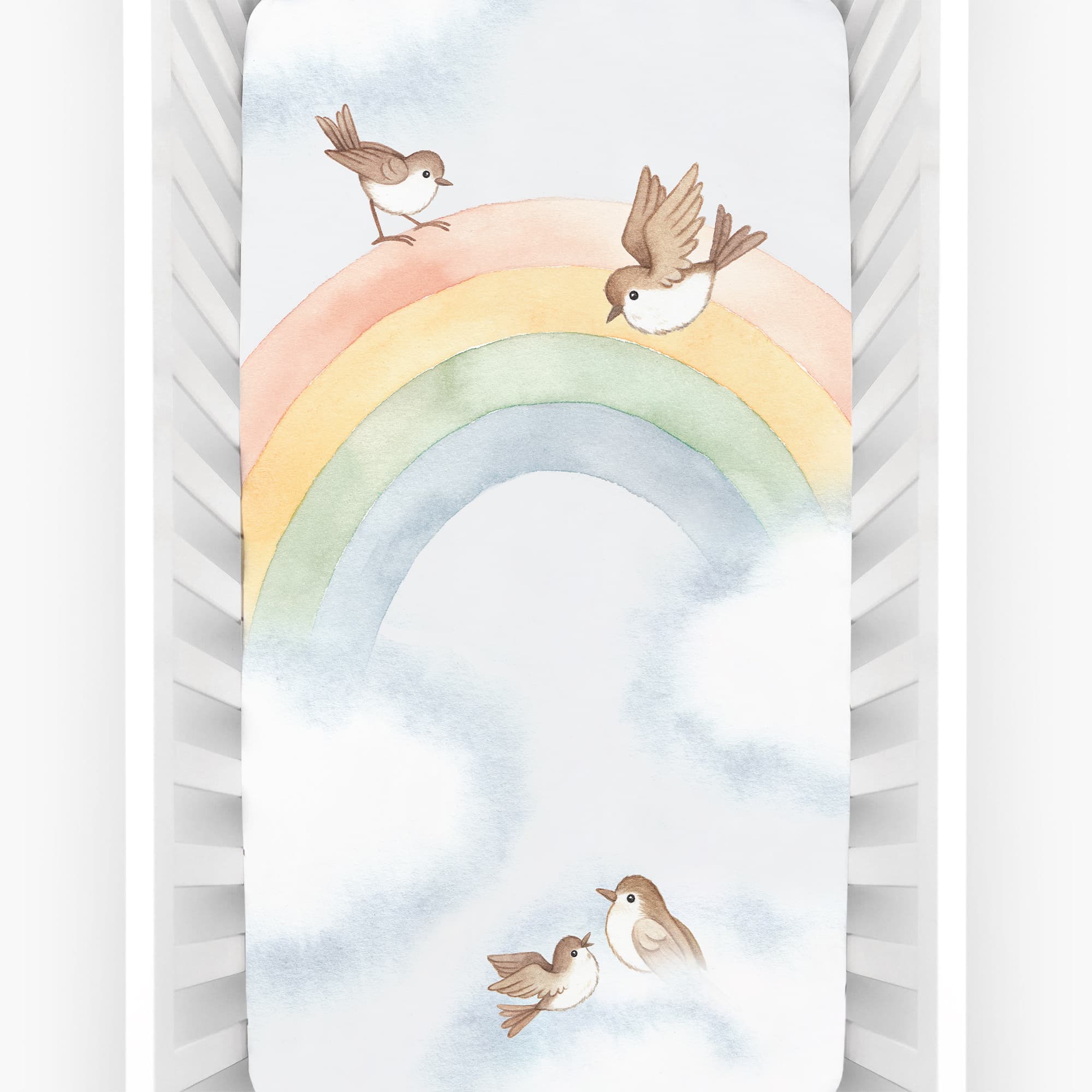 Baby crib sheet with watercolor rainbow design, light blue background, birds and clouds