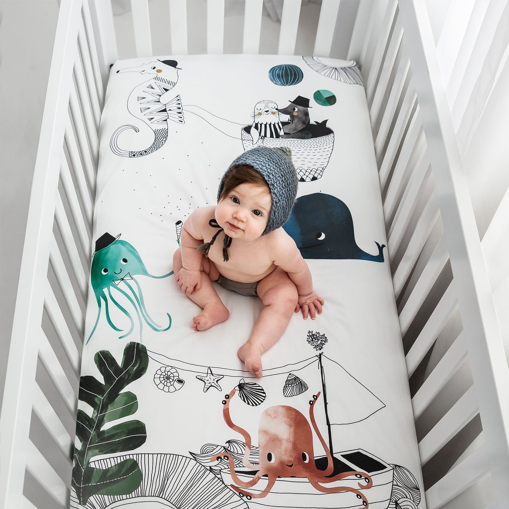 Fitted baby crib sheet by Rookie Humans, Underwater Love. Illustrated by Swanjte Hinrichsen. Designed for the modern nursery, packaged to make a unique baby shower gift. Nautical and ocean theme.