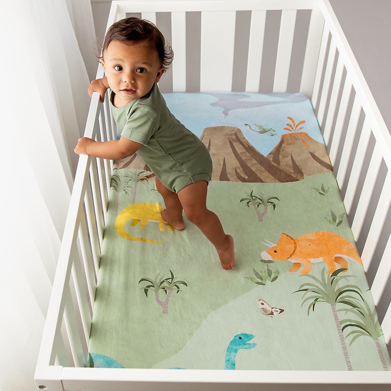 Dinosaur crib sheet with yellow orange and blue dinosaurs